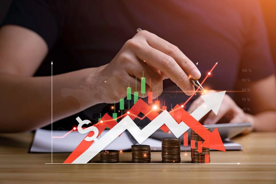 man calculating on table with an image overlay of a graph with lines going up and down indicating prices_